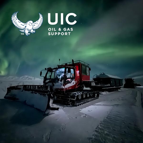dark winter scene with PistenBully tracked snow vehicle hauling fuel tanks. green northern lights in sky